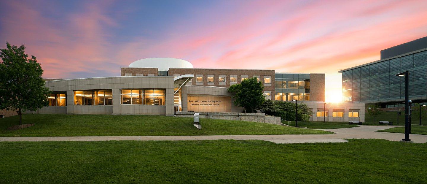 Elliott Hall on Oakland University's campus with the sun rising behind it.